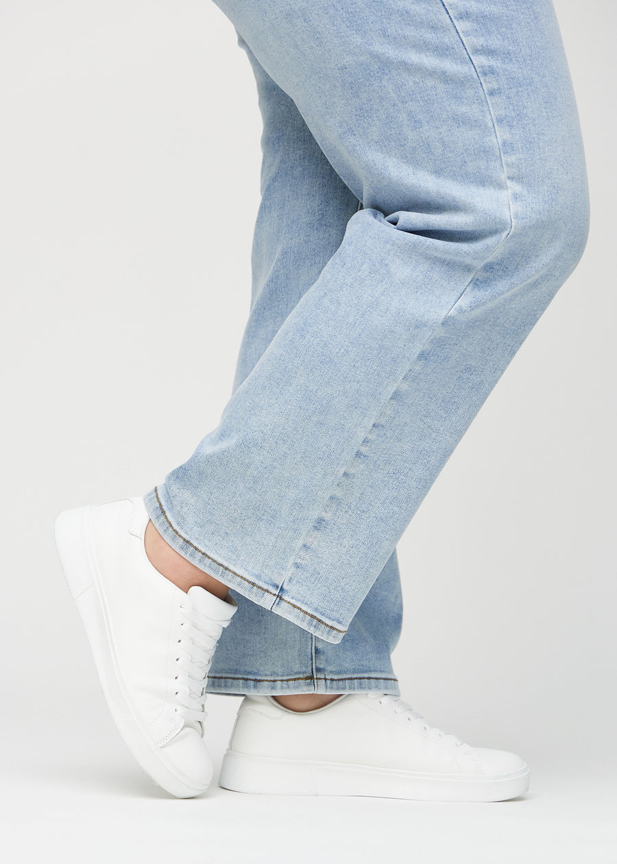 Loose jeans for women in light blue, color Waves. Close-up at the ankles on a plus-size model, showing the wide leg openings.