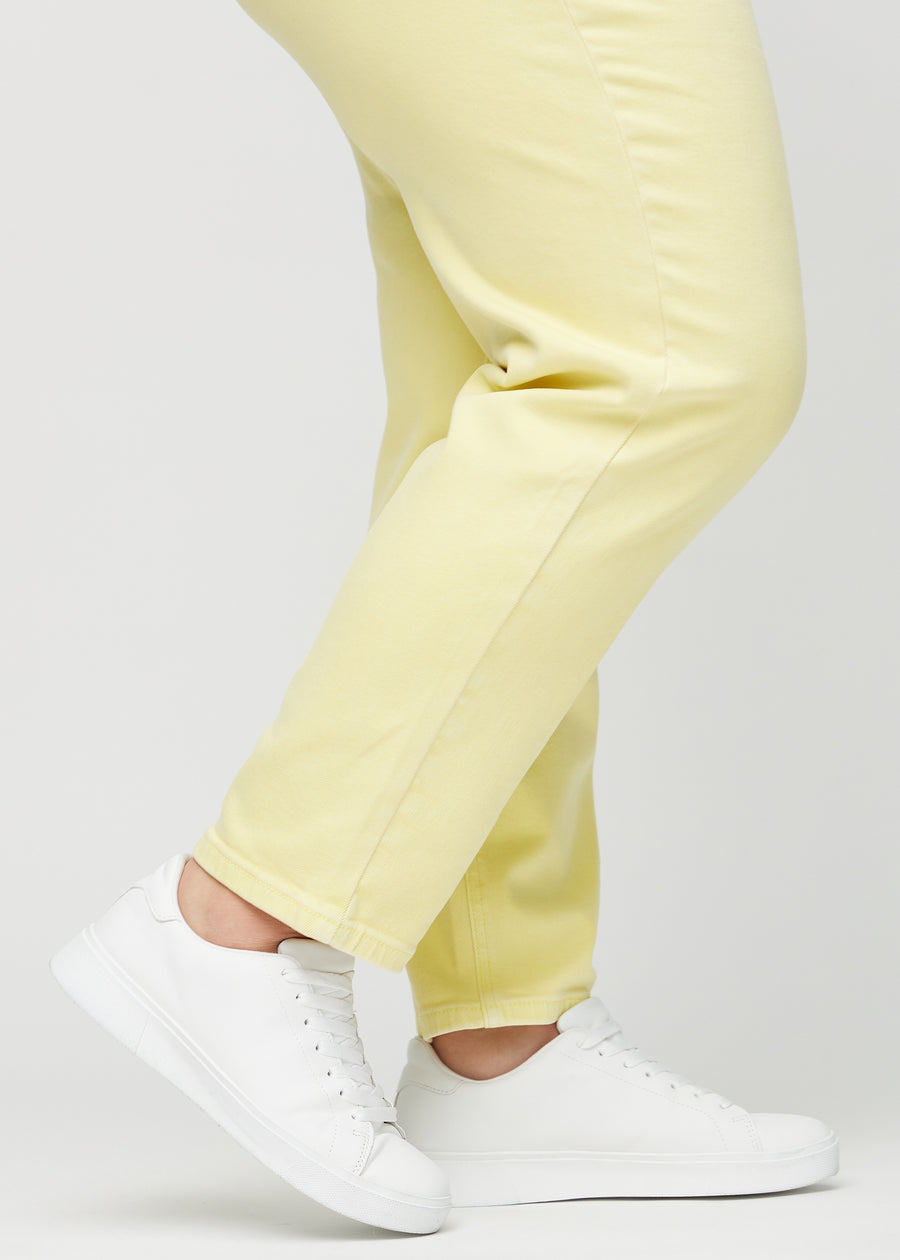 Regular jeans for women in light yellow, color Lemonades. Close-up at the ankles on a plus-size model, showing the straight leg openings.