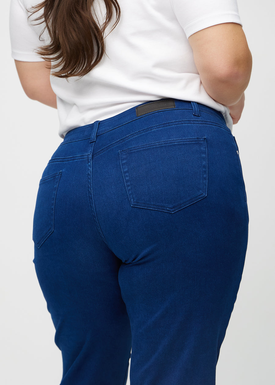 Regular jeans for women in dark blue, color Royals. Close-up from behind on a plus-size model, showing fit and details.
