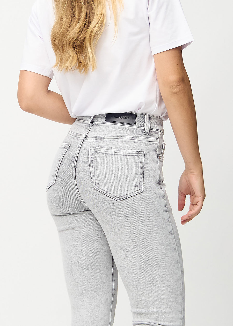 Skinny jeans for women in light grey, color Ashes. Close-up back view on a model, showing details.
