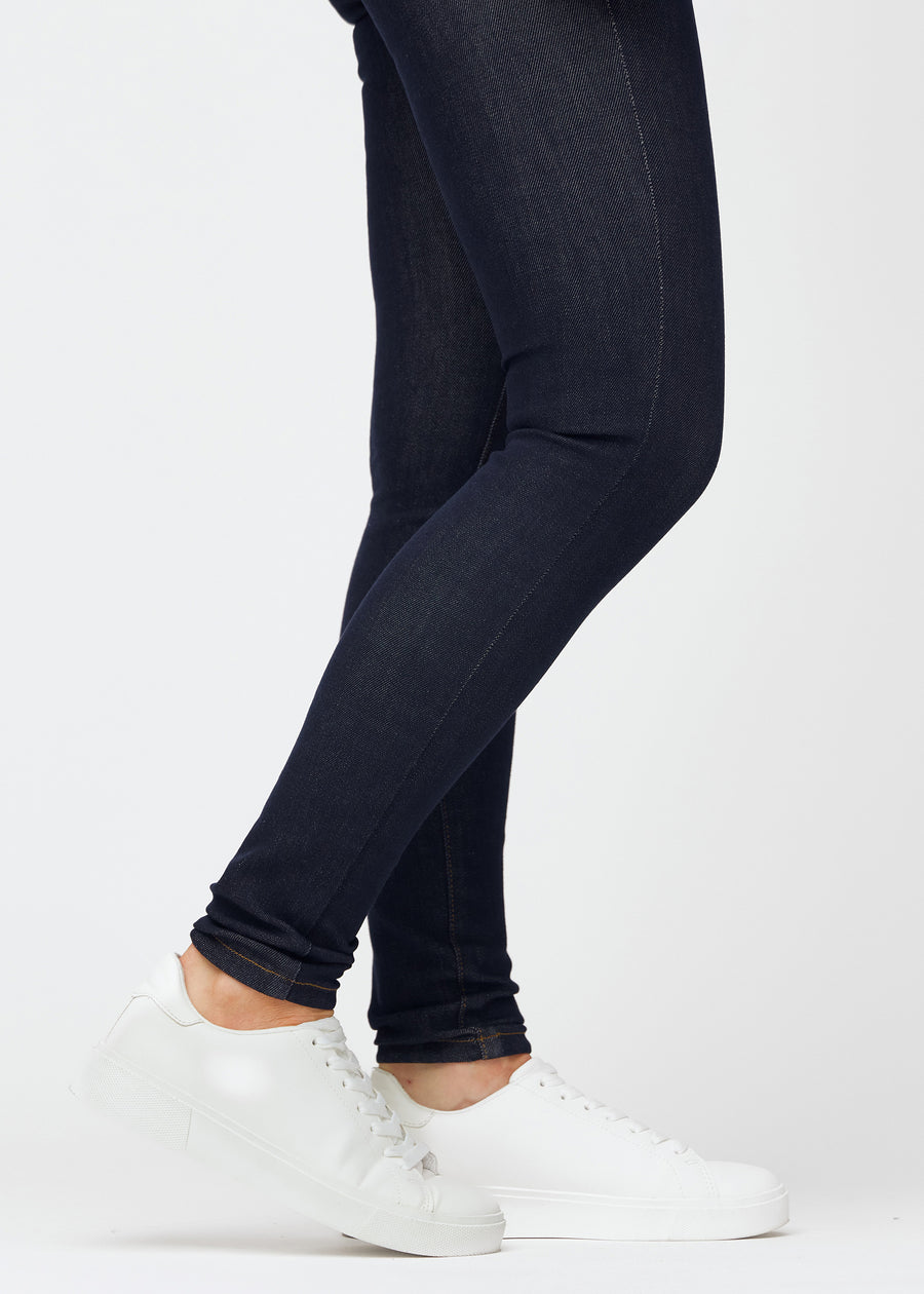 Deep dark blue denim jeans for women in the color Midnights with a skinny fit, shown close up at the ankles to display the close-fitting finish.