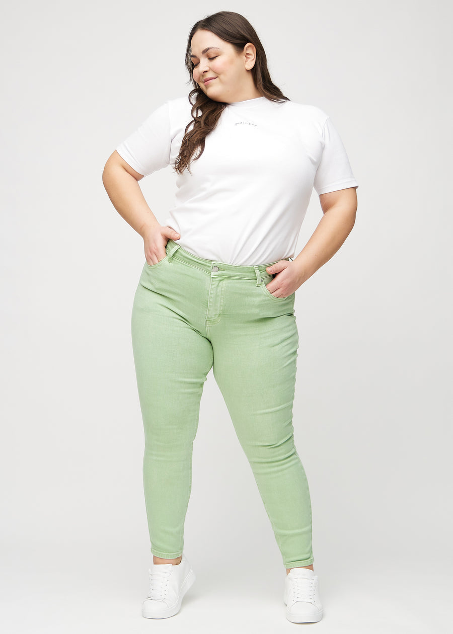 Skinny jeans for women in light green, color Mints. Full-length view of a plus-size model in the jeans.