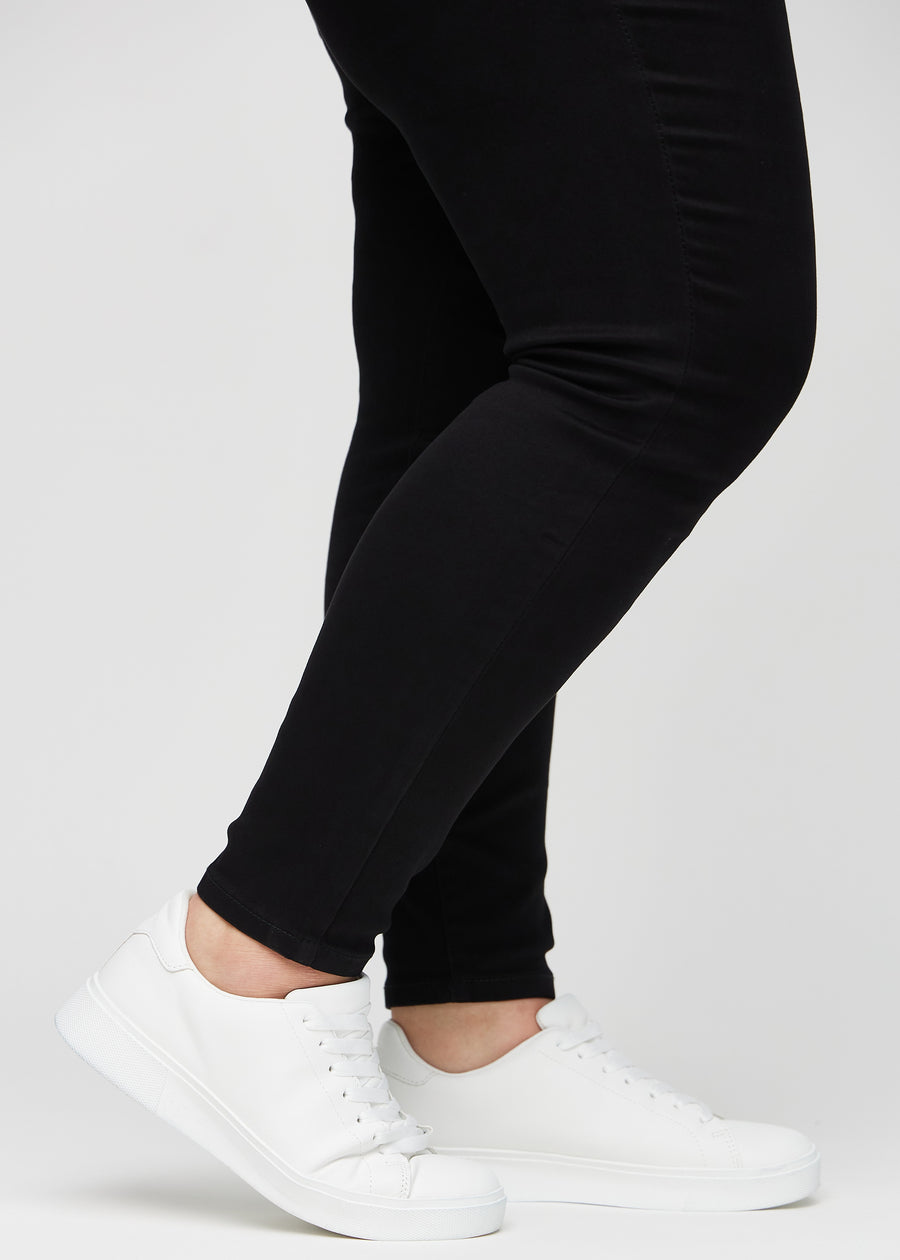The ankles of a plus-size model, so you can see how tightly the jeans fit in a Skinny fit.