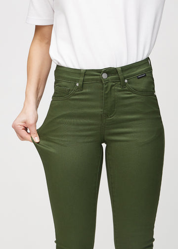 Skinny jeans for women in dark green, color Renewals. A model stretches the jeans at the thigh to show the fabric&