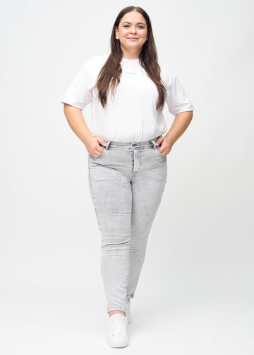 Slim jeans for women in light grey, color Ashes. Full-length view of a plus-size model wearing the jeans.
