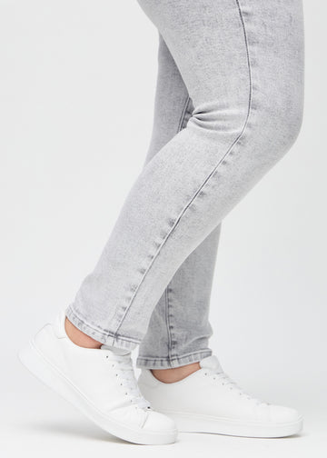 Slim jeans for women in light grey, color Ashes. Close-up at the ankles on a plus-size model, showing the fit at the leg openings.