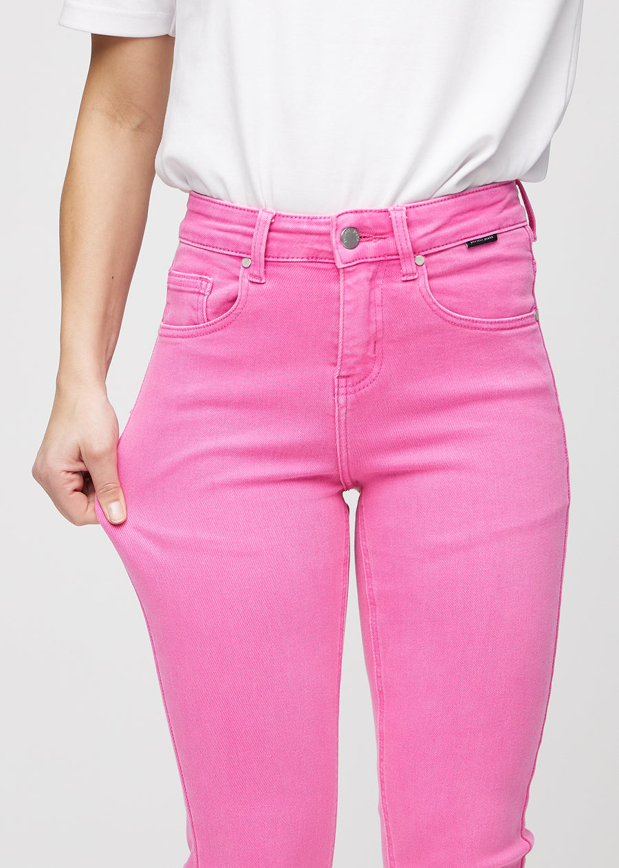 Slim jeans for women in light pink, color Flamingos. A model stretches the jeans at the thigh to show the fabric&