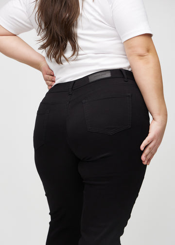Slim jeans for women in black, color Ravens. Close-up back view on a plus-size model, showing the details.