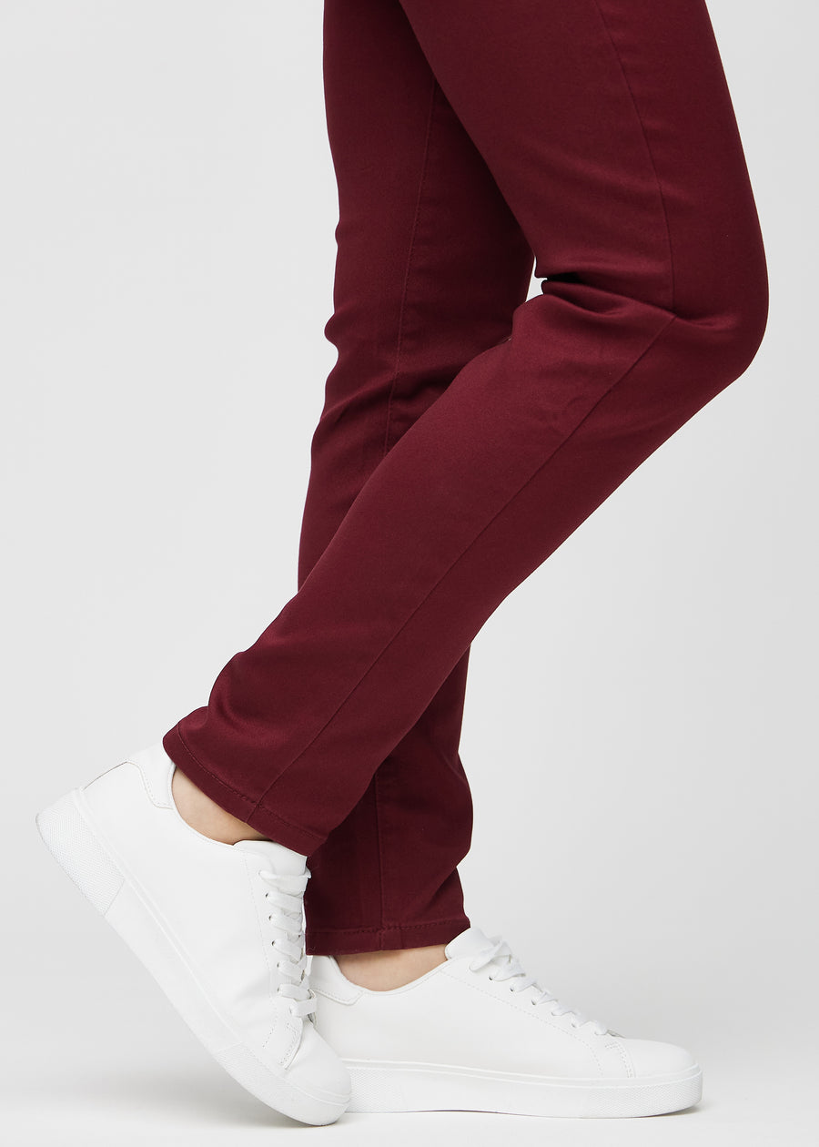 Slim jeans for women in dark red, color Santas. Close-up at the ankles on a model, showing the fit at the leg openings.
