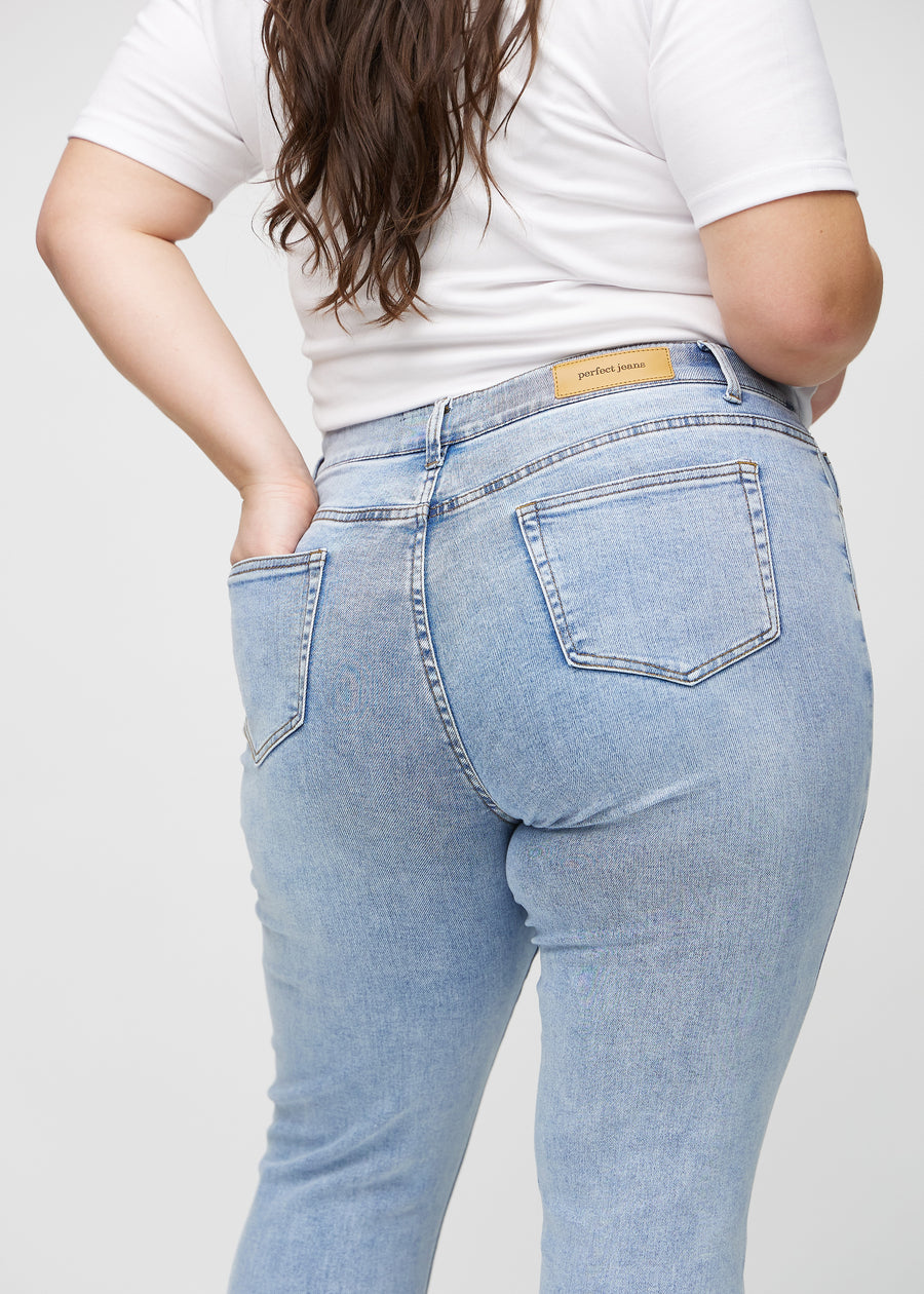 Slim jeans for women in light blue, color Waves. Close-up back view on a plus-size model, showing the details.