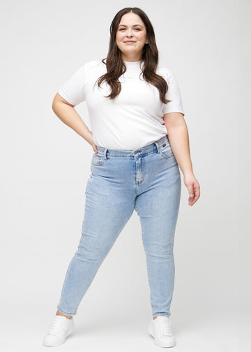 Slim jeans for women in light blue, color Waves. Full-length view of a plus-size model wearing the jeans.