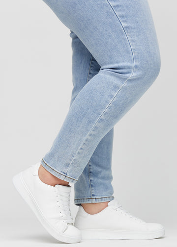 Slim jeans for women in light blue, color Waves. Close-up at the ankles on a plus-size model, showing the fit at the leg openings.