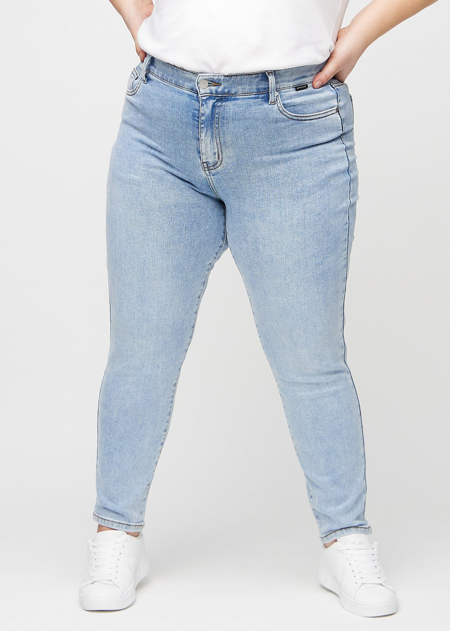 Slim jeans for women in light blue, color Waves. Front view on a plus-size model, showing a close fit through the leg with a little more room at the ankle.