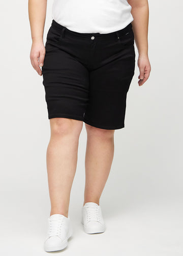 Black regular middle shorts, model name Ravens, which go straight down the leg and end just above the knee on a plus-size model, seen from the front.