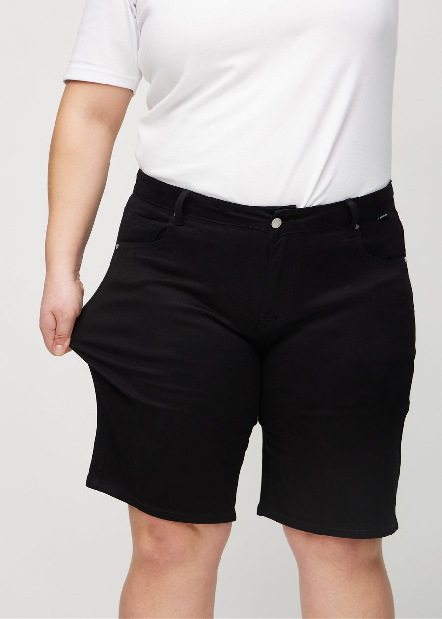 The plus-size model stretches the shorts at the thigh to show the stretch.