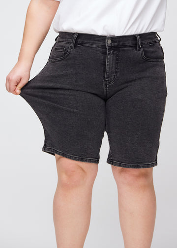 Plus-size model stretching the shorts at the thigh to show the stretch.