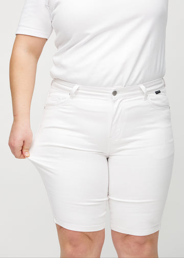The plus-size model stretches the shorts at the thigh to show the stretch.