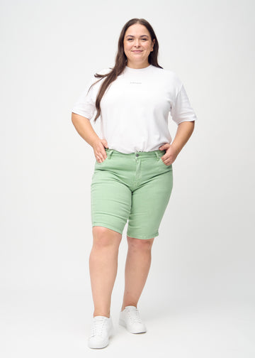 Full image of a plus-size model in light green skinny middle shorts.