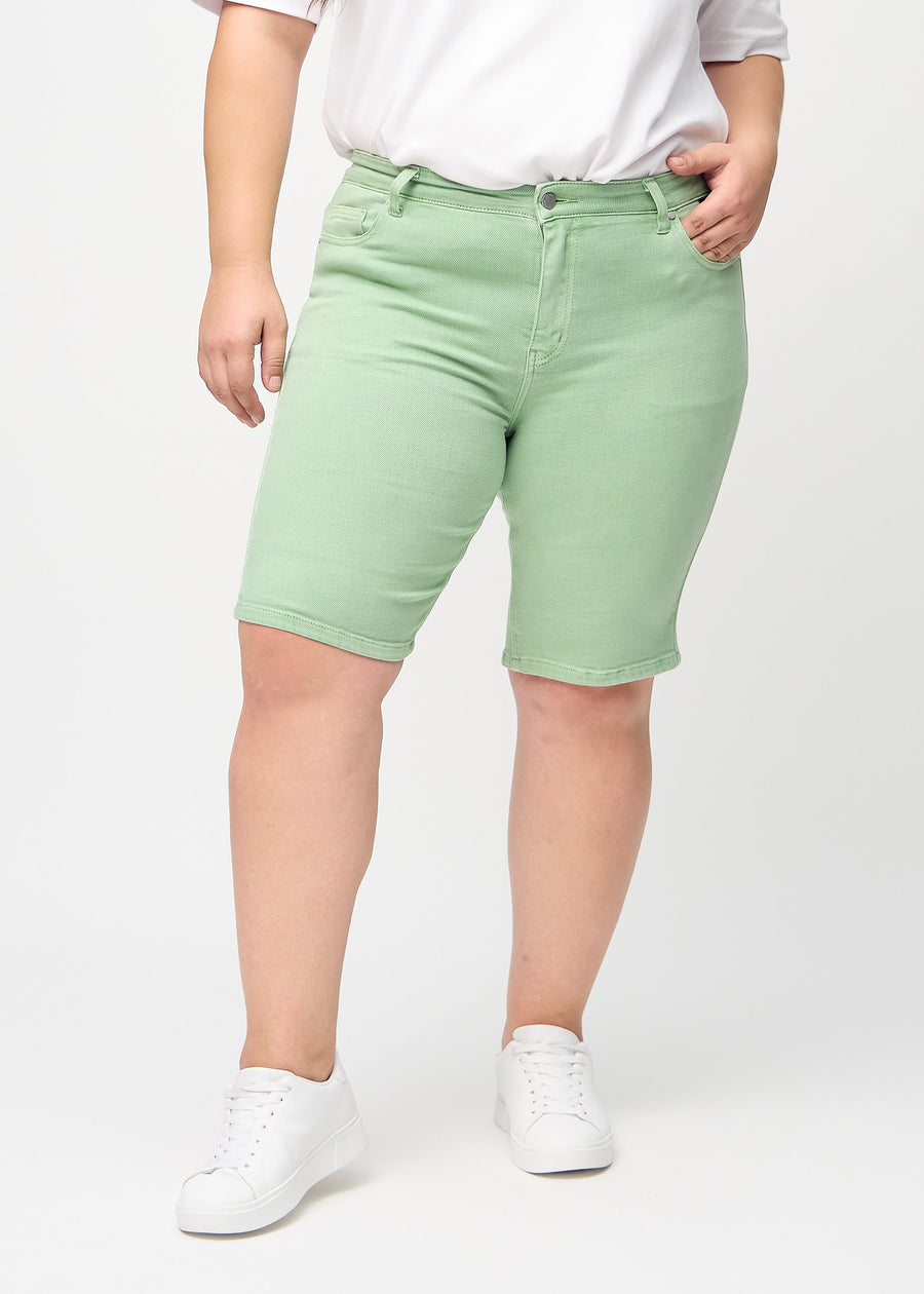 Light green skinny middle shorts, model name Mints, which fit tightly around the thigh and end just above the knee on a plus-size model, seen from the front.