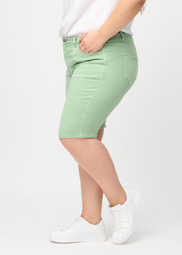 Light green skinny middle shorts seen from the side on a plus-size model.