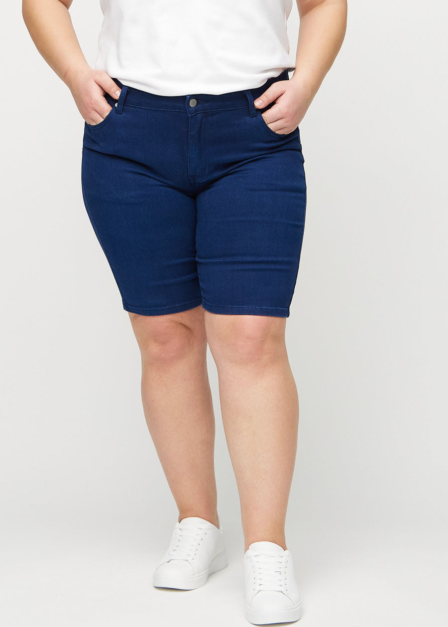 Dark blue skinny middle shorts, model name Royals, which fit tightly around the thigh and end just above the knee on a plus-size model, seen from the front.