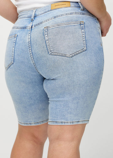 Light denim skinny middle shorts seen from the back close up on a plus-size model to show details.