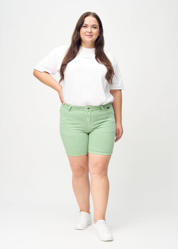 Full image of a plus-size model in light green skinny short shorts.