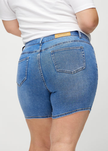 Denim skinny short shorts seen from the back close up on a plus-size model to show details.