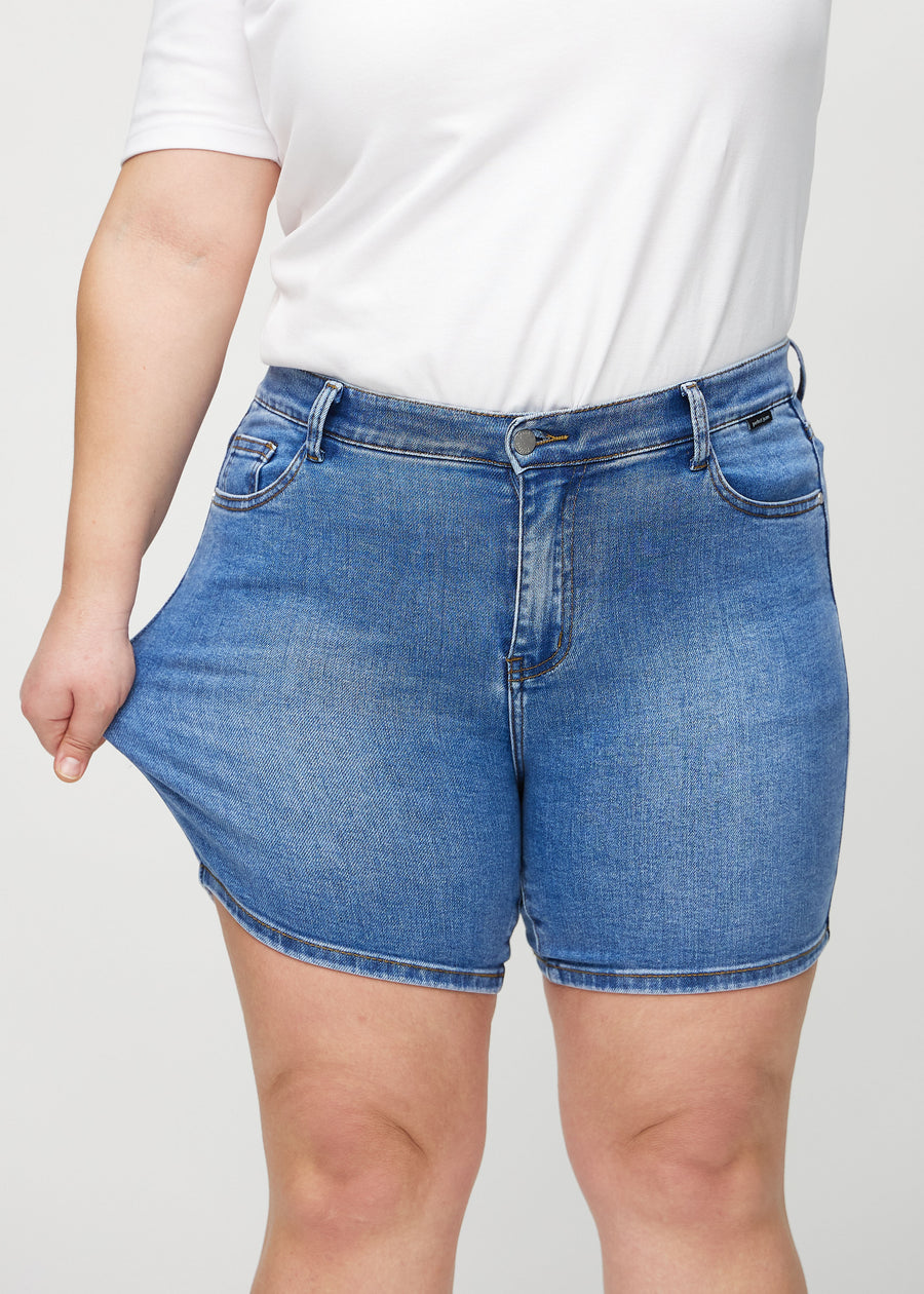 The plus-size model stretches the shorts at the thigh to show the stretch.