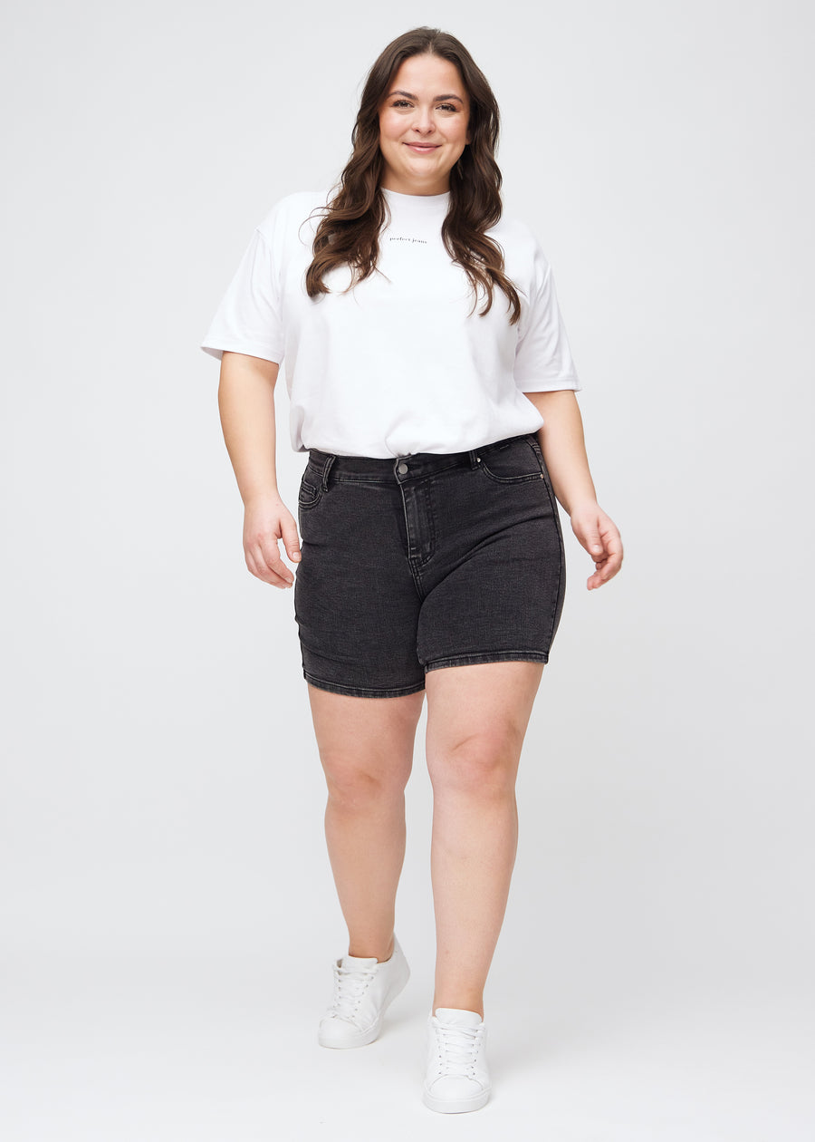 Full image of a plus-size model in dark grey denim skinny short shorts.