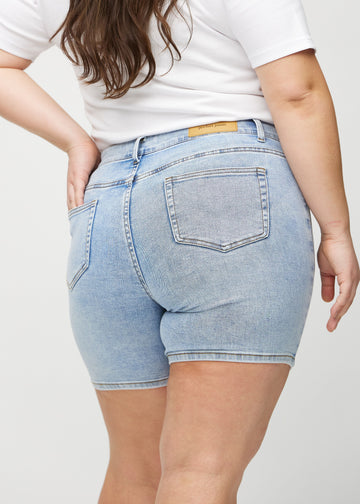 Light denim skinny short shorts seen from the back close up on a plus-size model to show details.