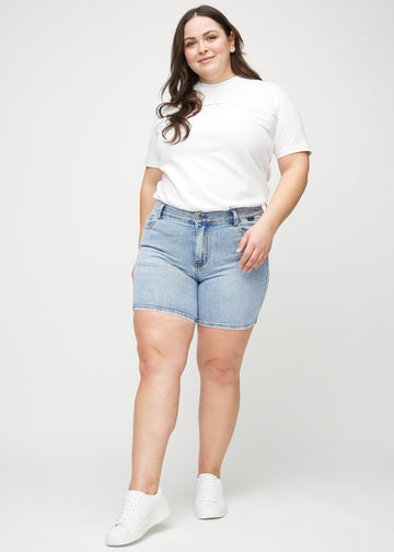 Full image of a plus-size model in light denim skinny short shorts.