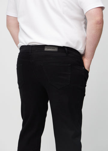 Black regular jeans seen from the back in a close-up on a plus-size model to show details.