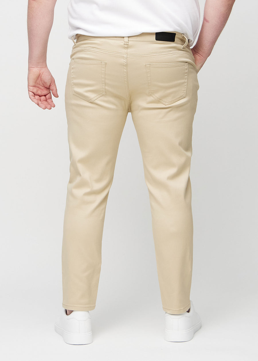 Beige slim jeans viewed from the back on a plus-size model to show the full product.
