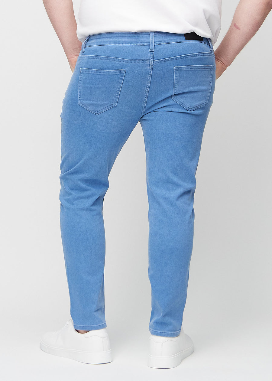 Blue slim jeans viewed from the back on a plus-size model to show the full product.