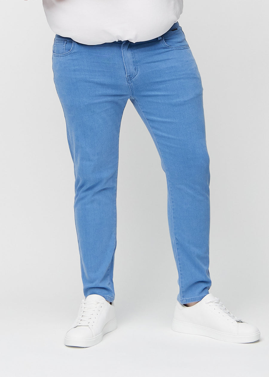 Blue slim jeans, model name Geraniums, fitted closely along the legs on a plus-size model, front view.