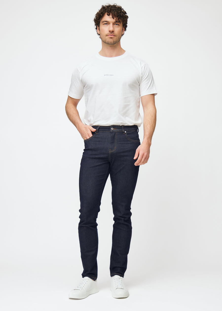 Full image of model in deep dark blue denim jeans for men in the color Midnights with a slim fit.