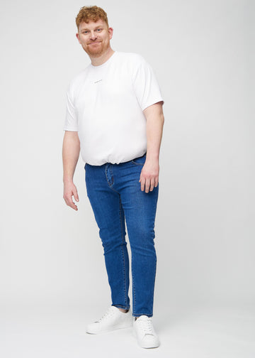 Fuldt billede af en plus-size model i mørk denim slim jeans.