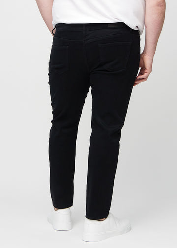 Black slim jeans viewed from the back on a plus-size model to show the full product.