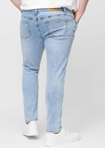 Light blue denim slim jeans viewed from the back on a plus-size model to show the full product.