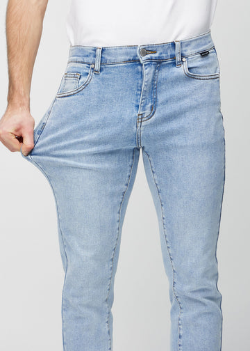 Model stretches the jeans at the thigh to show the fabric&