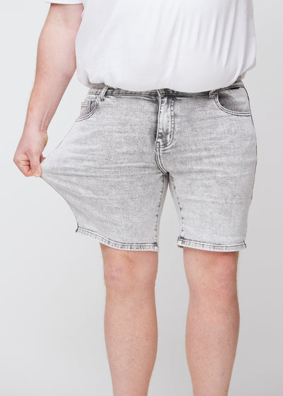 Plus-size model strækker shortsene ved låret for at vise stretch.