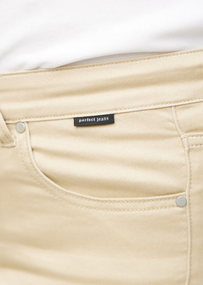 Forlommen på et par beige loose jeans, hvor man kan se logoet på en plus-size model.