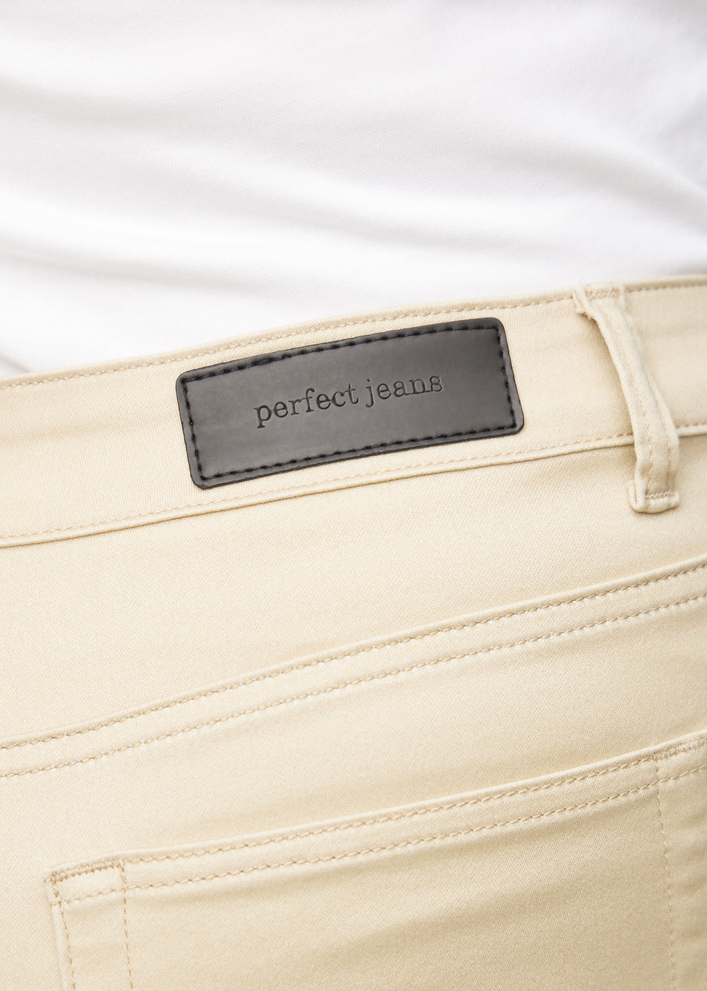 Baglommen på et par beige loose jeans, hvor man kan se logoet på en plus-size model.