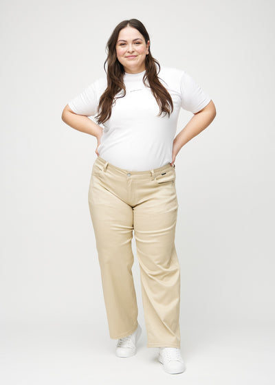 Plus-size model går ind i billedet, strækker i jeansene, viser dem frem ved at dreje rundt, og forlader derefter billedet.