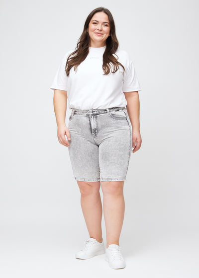 Plus-size model går ind i billedet, strækker i sine shorts, viser dem frem ved at dreje rundt, og forlader derefter billedet.