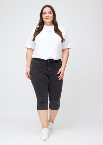 Plus-size model går ind i billedet, strækker i sine capris, viser dem frem ved at dreje rundt, og forlader derefter billedet.