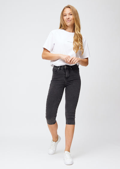Model går ind i billedet, strækker i sine capris, viser dem frem ved at dreje rundt, og forlader derefter billedet.