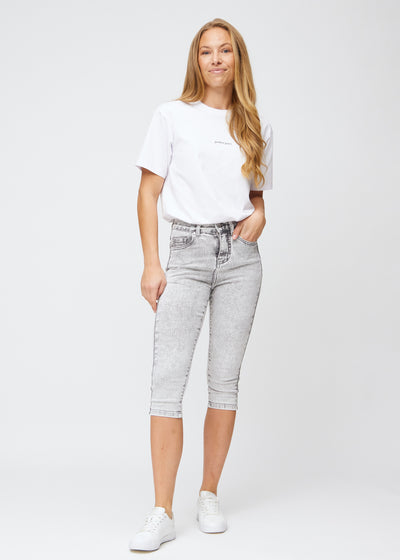 Model går ind i billedet, strækker i sine capris, viser dem frem ved at dreje rundt, og forlader derefter billedet.